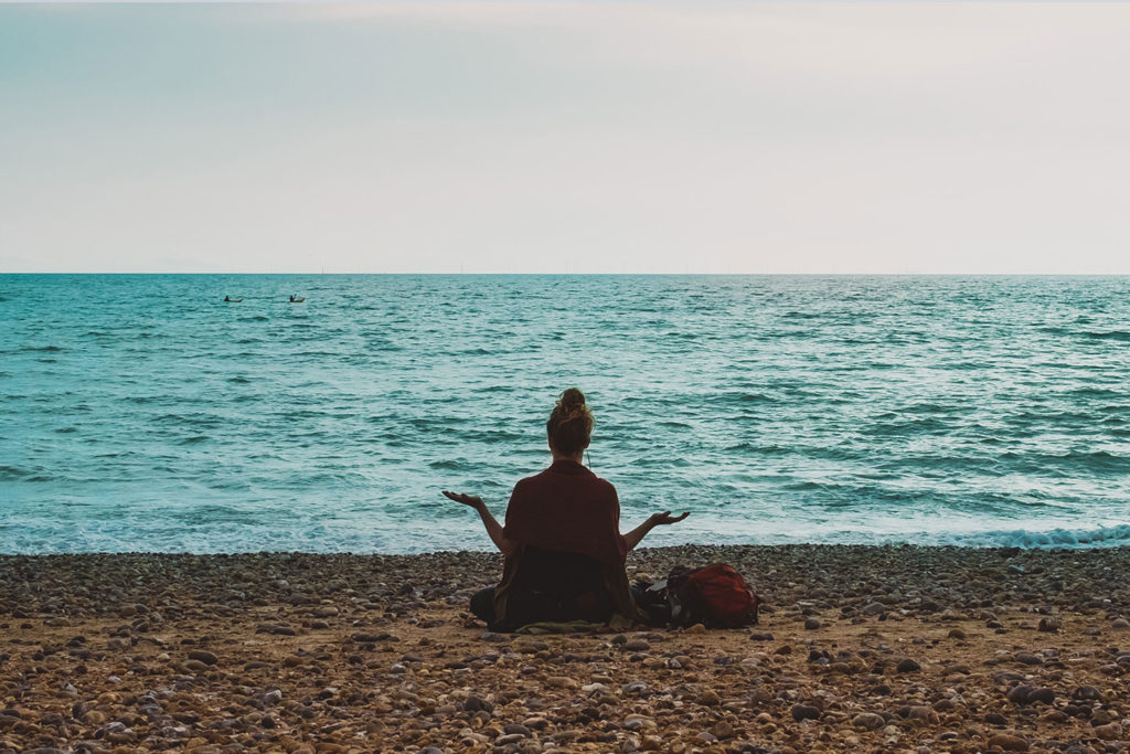 a woman meditating ocean side