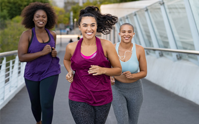 Three woman smiling on a run outside