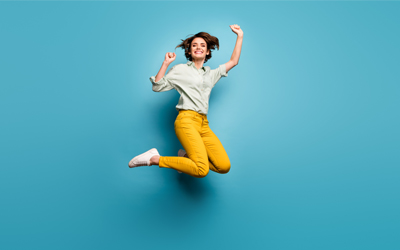 Woman in green shirt and yellow pants jumping for joy