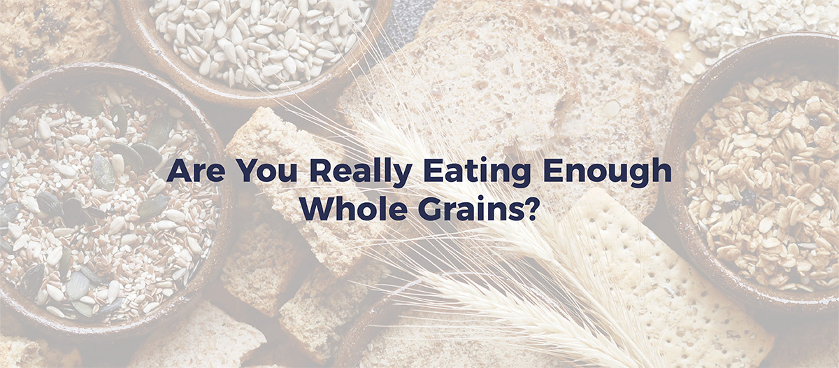 Grains, crackers, wheat, and bread on a table. Text reads "Are you really eating enough whole grains"