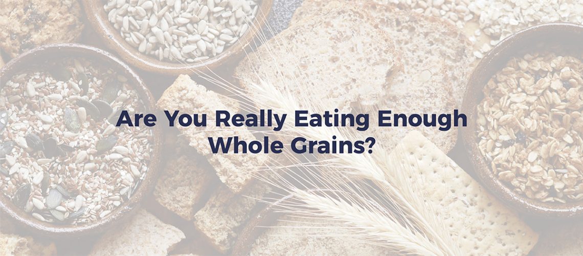 Grains, crackers, wheat, and bread on a table. Text reads "Are you really eating enough whole grains"