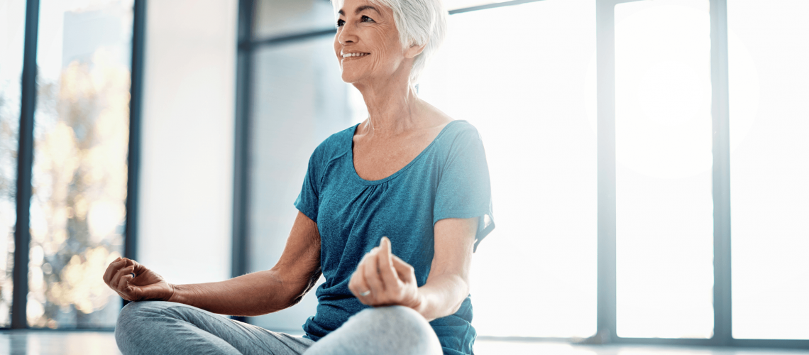 older woman smiling and sitting in yoga pose
