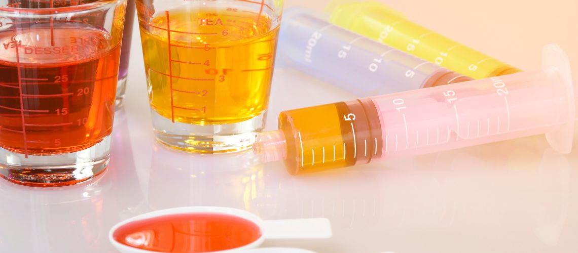 various liquid medicines in syringes, measurement spoons and cups.
