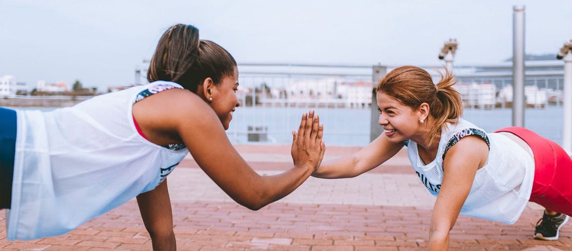 two women locking hands during workout